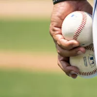 Close-up of pitcher's leg with two baseballs held in hand.
