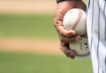 Close-up of pitcher's leg with two baseballs held in hand.