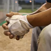 Baseball player's hands folded over knees on bench