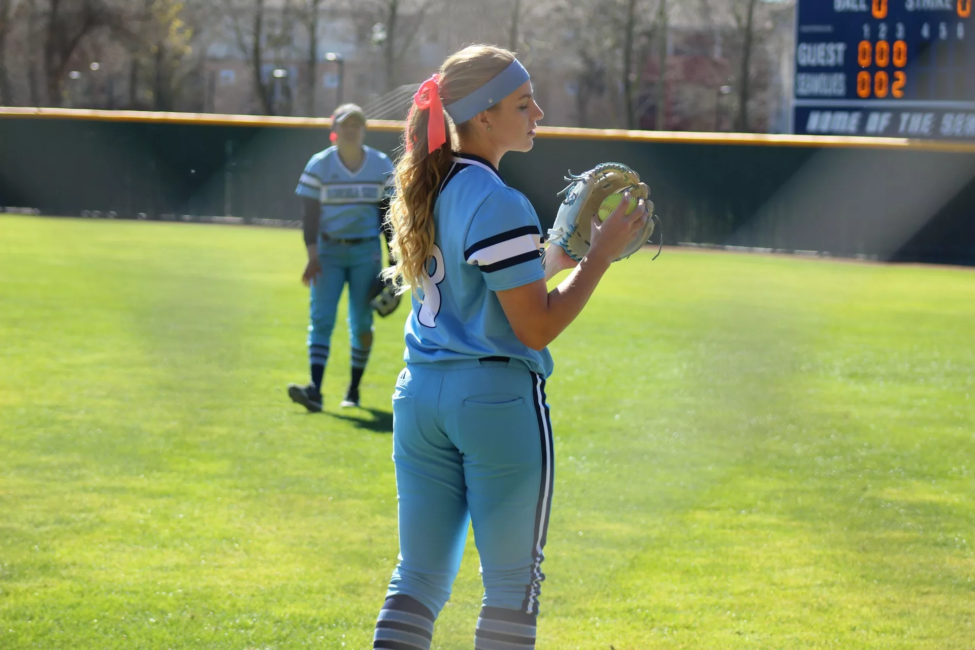 Two female softball players playing catch while warming up for their game.
