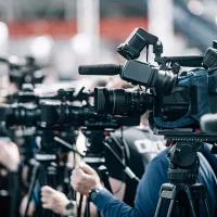 Multiple manned cameras pointed in one direction at a press conference