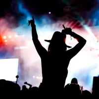 femela concertgoer in silhouette in front of stage lights^ watching show