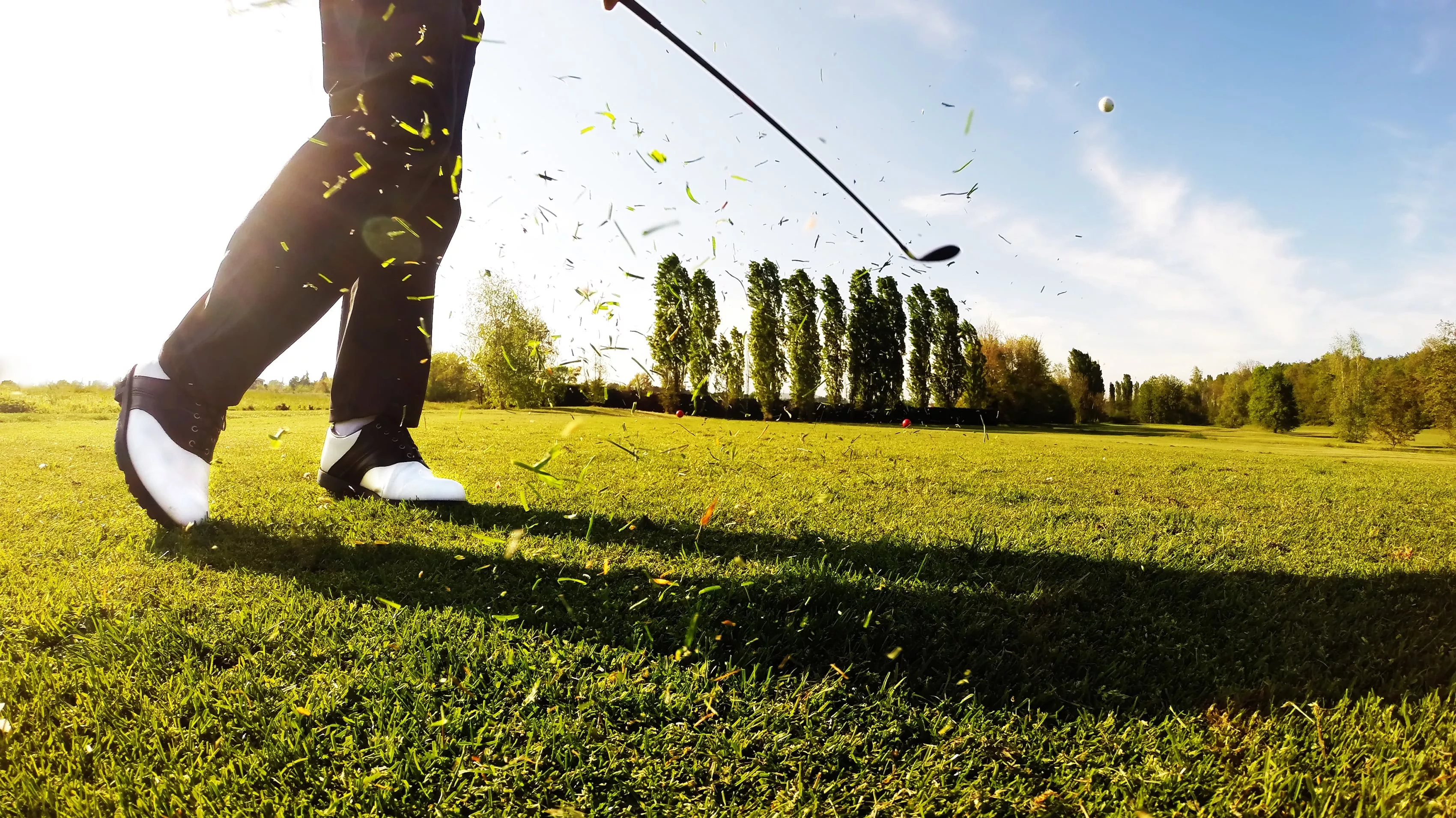 Golfer performing a powerful golf shot on a sunny day.