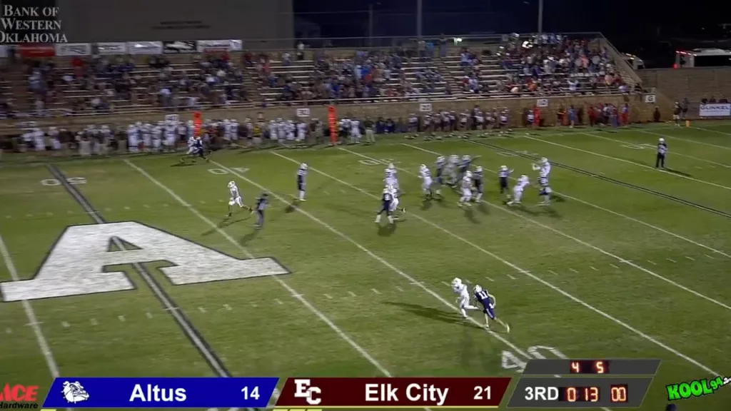 Football game between Elk City and Altus High Schools with a punt in action. The scoreboard shows Elk City leading 21-14 with 13 seconds left in the third quarter.