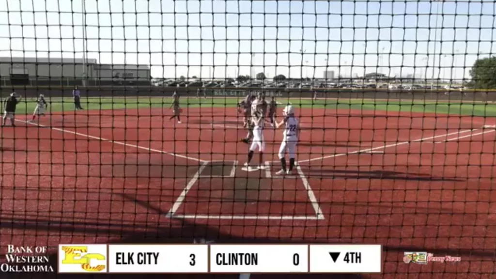 Elk City Elkettes celebrate after a 2-run score against Clinton, leading 5-0 in the 4th inning, though the scoreboard still shows 3-0.