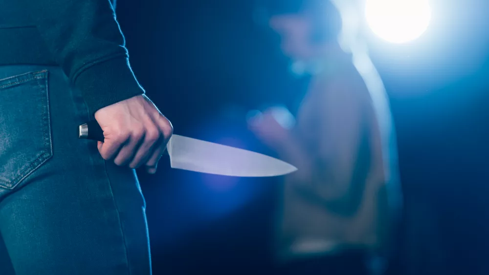 cropped-view-of-killer-holding-knife-near-woman-on-black