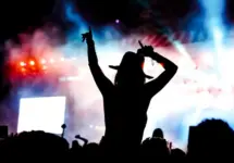 femela concertgoer in silhouette in front of stage lights^ watching show