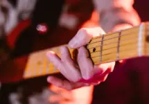 Close up look of hands of a man playing the electric guitar during a concert
