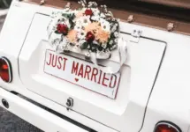 'JUST MARRIED" sign with flower decoration on white wedding car
