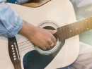 Close up woman's hands playing acoustic guitar.