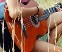 female country artist playing guitar outdoors