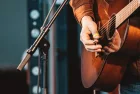 close up of hand of man playing guitar in concert on stage