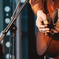 close up of hand of man playing guitar in concert on stage