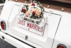 'JUST MARRIED" sign with flower decoration on white wedding car