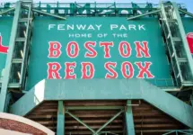 View of the historic architecture of the Fenway Park Stadium showcasing its signs^ brick walls^ statues^ and the famous green color and red letters of the red sox. Boston^ MA^ USA - March 10^ 2023