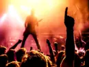 view from crowd cheering rock band performing on stage^ guitarist in silhouette