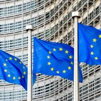 A row of flags of the European Union flying in the wind in front of the Berlaymont building^ seat of the European Commission in Brussels^ Belgium.