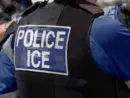 ICE police agent - Officer of Immigration and Customs Enforcement. Close-up of POLICE ICE marking on the back of a stab proof vest uniform worn by a trio of police officers at the scene of an immigrant incident. The ICE federal law enforcement agency is under the supervision of the United States Department of Homeland Security.