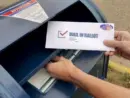 A man puts an absentee mail-in ballot in the mailbox. Circa August^ 2020
