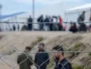 Barbed wire in refugee camp. Migrants behind chain link fence in camp. Group of people behind fence. Concept of prison^ freedom^ barrier^ security and migration. Refugees on their way to EU.