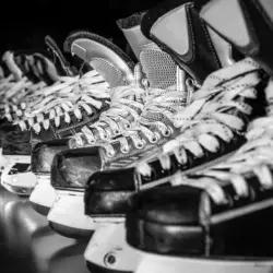 Pairs of hockey skates lined up in a locker room