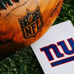 New York Giants NFL team Logo and American football ball on Green Grass. NEW YORK^ USA^ FEBRUARY 10^ 2025