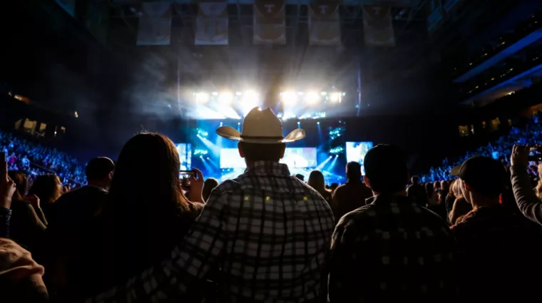 A country music fan watches a live concert wearing a cowboy hat.