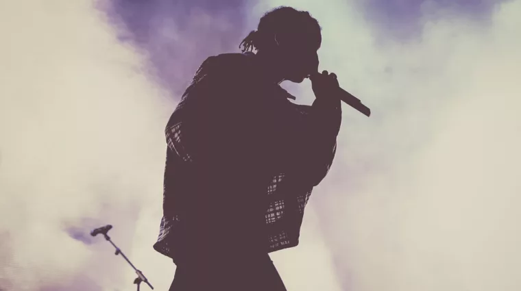 silhouette of rapper (male) performing on stage with mic