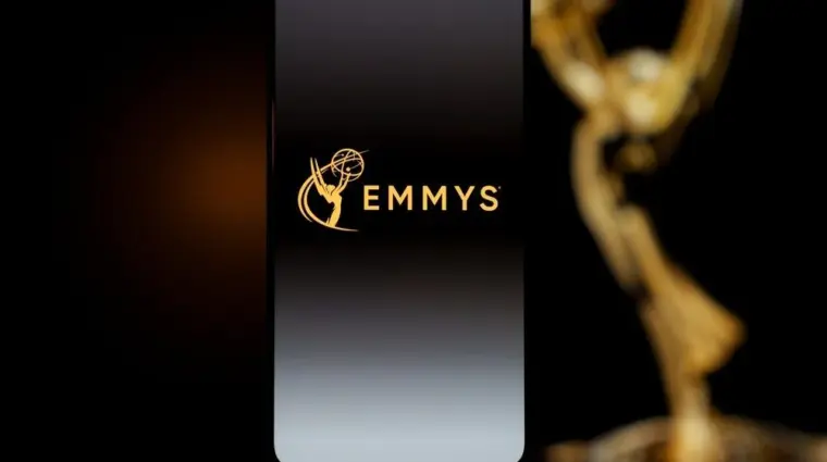 Emmys logo displayed on a smartphone screen with a blurred gold award statuette in the background^ television industry awards and digital streaming concept. Kaunas^ Lithuania - 2026 March 24