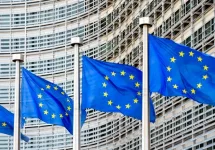 A row of flags of the European Union flying in the wind in front of the Berlaymont building^ seat of the European Commission in Brussels^ Belgium.