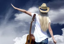 Young woman with guitar on the road and her vintage baggage