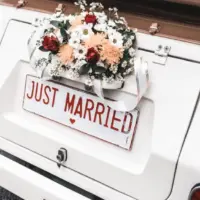 'JUST MARRIED" sign with flower decoration on white wedding car