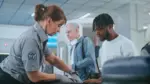Security Checkpoint in Airport Terminal: Female TSA Worker Inspecting Baggage of Passenger before Boarding Flight^ Finding and Confiscates Liquid. Queue of Diverse People During Screening Procedures.