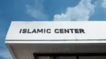 Islamic Center sign on a community building under blue sky^ symbolizing worship^ cultural education^ Muslim community services^ faith^ and spiritual guidance