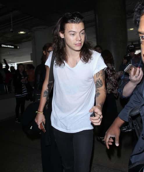01/20/2016 - Harry Styles - Harry Styles Sighted at LAX Airport on January 20, 2016 - Los Angeles International Airport - Los Angeles, CA, USA - Keywords: 3/4 Length Shot, Torn Black Pants, Ring, Rings, Bracelet, Necklace, Jewelry, Tattoo, Tattoos, White Shirt, Shoulder Length Wavy Brown Hair, Vertical, boy band, man, men, musician, performer, singer, 1 Direction, Vertical, Performer, Musician, Music, Celebrity Sighting, Celebrities, Arts Culture and Entertainment, Photography, Person, People, California, Candid, Walking, Travel Orientation: Portrait Face Count: 1 - False - Photo Credit: STPR / PRPhotos.com - Contact (1-866-551-7827) - Portrait Face Count: 1