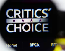 Photo of Critics' Choice Awards homepage on a monitor screen through a magnifying glass.