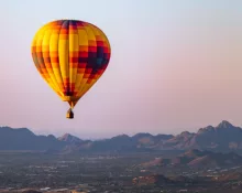 Hot air balloon flies over phoenix^ Arizona with Sonoran Desert in background