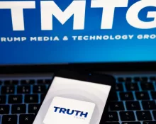 Truth Social app logo seen on the smartphone and blurred TMTG logo on the laptop.