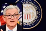 Federal Reserve (Fed) Chair Jerome Powell is visible on smartphone screen. In the background^ an inflation rate chart is displayed.