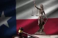 Texas US state flag with statue of lady justice^ constitution and judge hammer on black drapery.