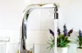 Open kitchen sink faucet flowing stream of water purified by domestic reverse osmosis with filters around. Front view. Horizontal composition.