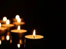 Burning candles on mirror surface in darkness^ closeup