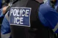 ICE police agent - Officer of Immigration and Customs Enforcement. Close-up of POLICE ICE marking on the back of a stab proof vest uniform worn by a trio of police officers at the scene of an incident