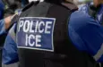 ICE police agent - Officer of Immigration and Customs Enforcement. Close-up of POLICE ICE marking on the back of a stab proof vest uniform worn by a trio of police officers at the scene of an immigrant incident. The ICE federal law enforcement agency is under the supervision of the United States Department of Homeland Security.