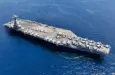 Aerial drone photo of USS Gerald R. Ford latest technology nuclear powered aircraft carrier anchored in deep blue open ocean sea