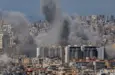 Multiple large plumes of thick grey smoke billow from residential apartment complexes following an explosion or missile strike in a crowded urban skyline. Jan 3 2021 in Iran