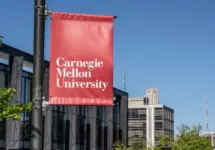 Carnegie Mellon University campus entrance sign with buildings in the background. Pittsburgh^ Pennsylvania^ USA- May 13^ 2021: Carnegie Mellon University campus entrance sign with buildings in the background. CMU is a private research university