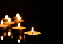 Burning candles on mirror surface in darkness^ closeup