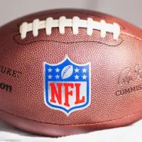 NFL Wilson Duke ball over a white sofa in a home. Sun light comes from a window.