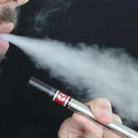 Bearded man vaping against black background